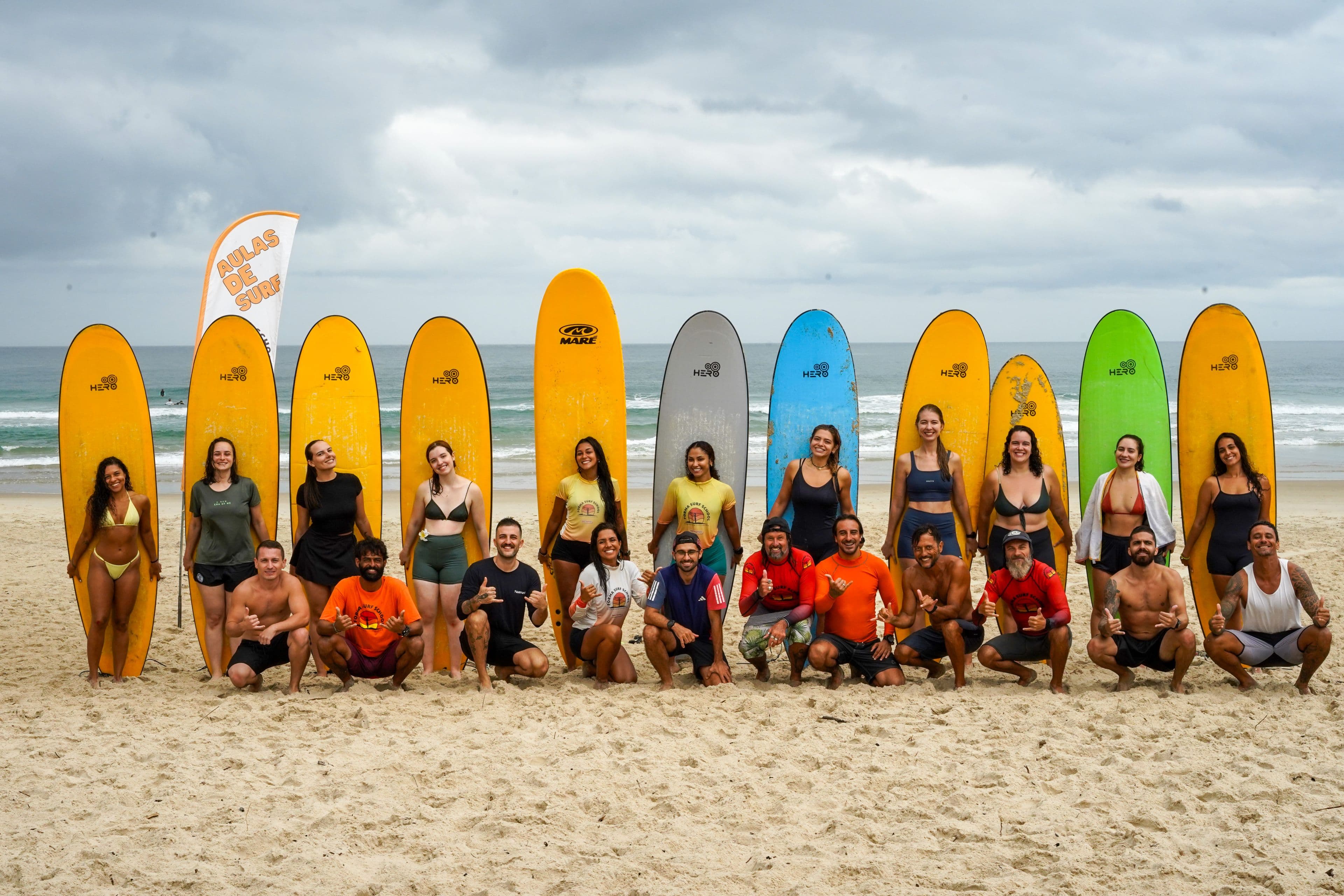 Alunos e instrutores da Forma Surf School reunidos na praia com pranchas de surf